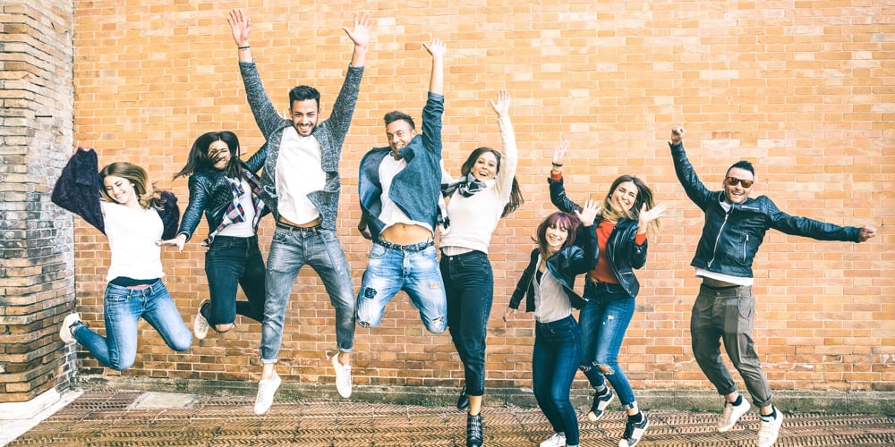 Happy Friends Millennials Jumping And Cheering Against Brick Wall In The City – Friendship Lifestyle