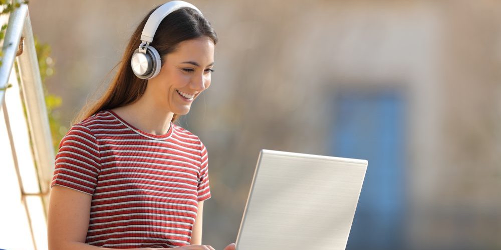 Happy Student E Learning Wearing Headphones And Using A Laptop S