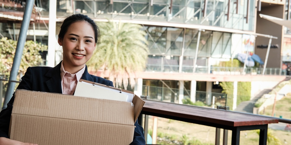 Happy Woman Resigning Her Job & Holding Cardboard Box Containing Personal Belongings. Resignation Co