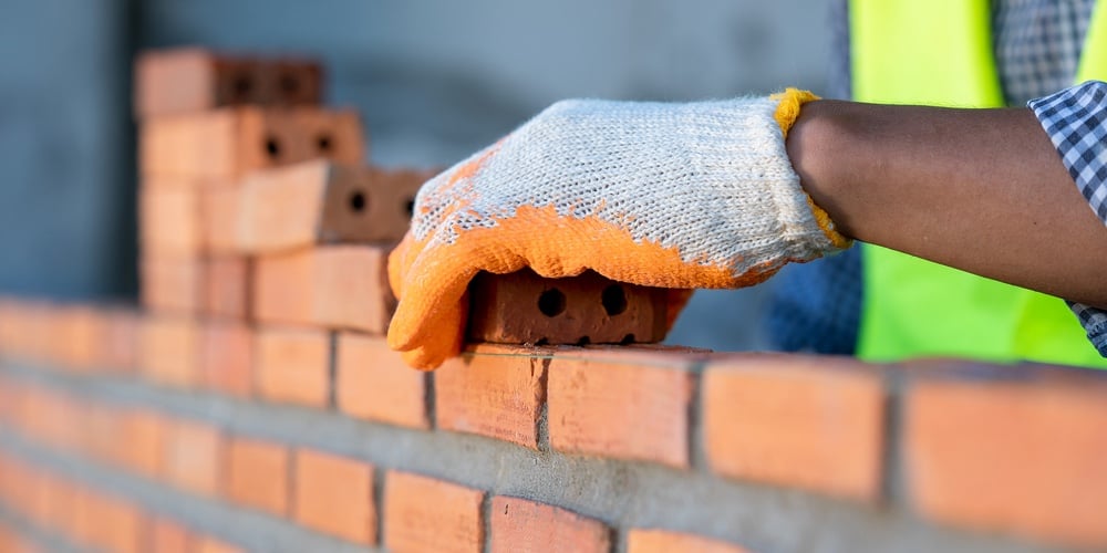 Industrial Bricklayer Installing Bricks On Construction Site