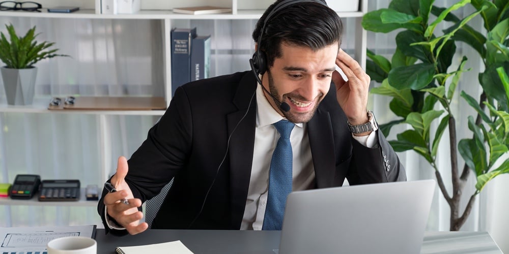 Male Call Center Operator Or Telesales Representative Siting At His Office Desk Wearing Headset And