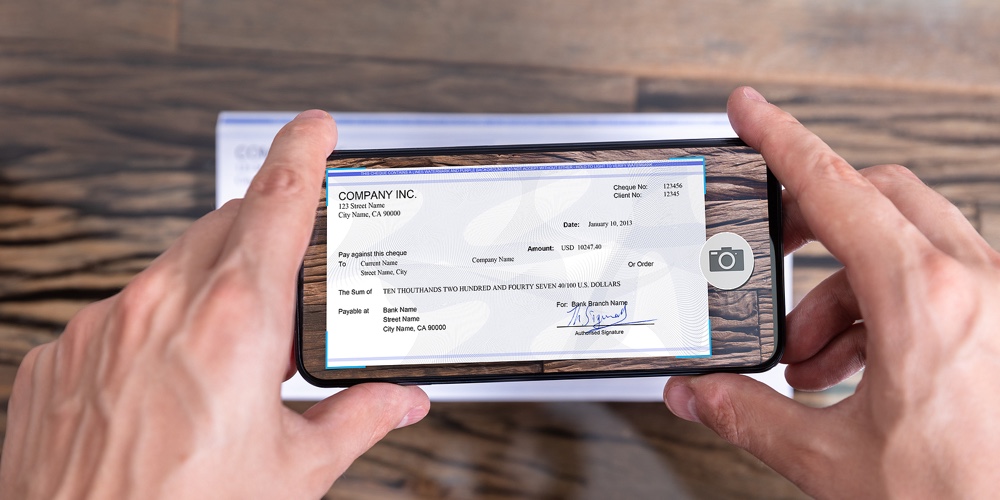 Man Taking Photo Of Cheque To Make Remote Deposit In Bank