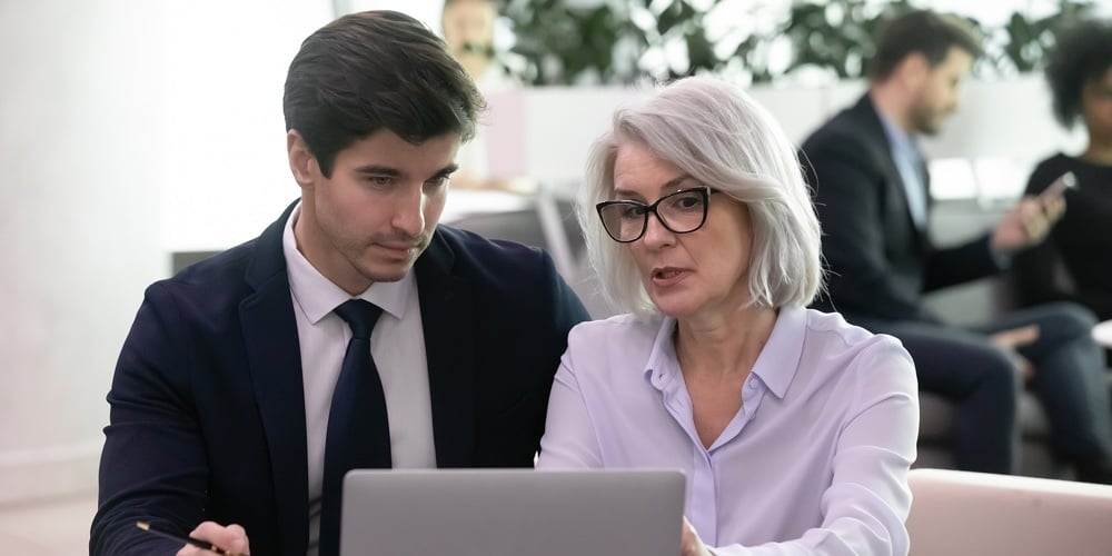 Mature Businesswoman Use Laptop Discussing Business Plan With Younger Colleague