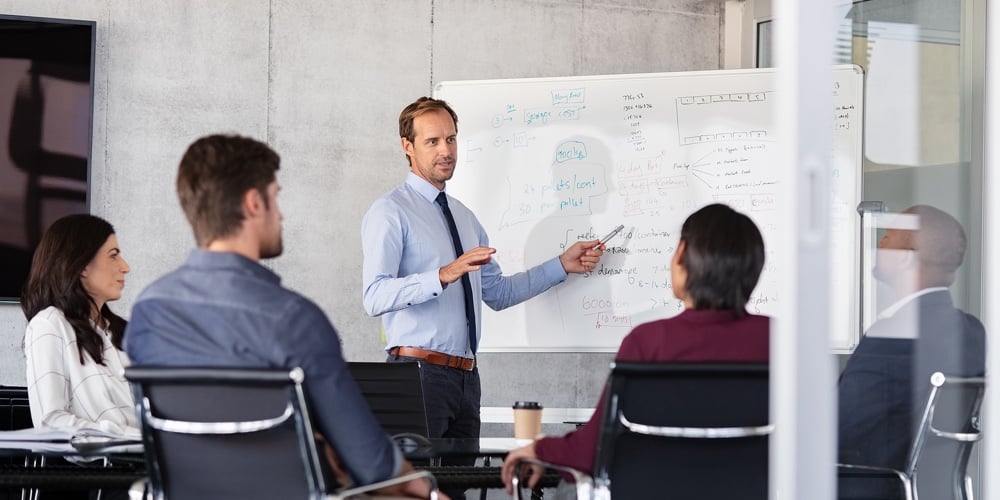 Mature businessman giving presentation to his colleagues in modern office. Leader presenting new pro