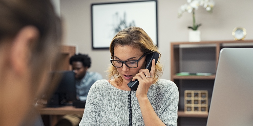 Mature businesswoman talking on phone in office. Casual business woman talking on landline phone in