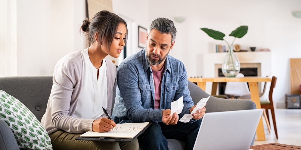 Overdraft Sign And Stack Of Accounting Documents.|Mature couple calculating bills at home using laptop. Multiethnic couple working on computer while c