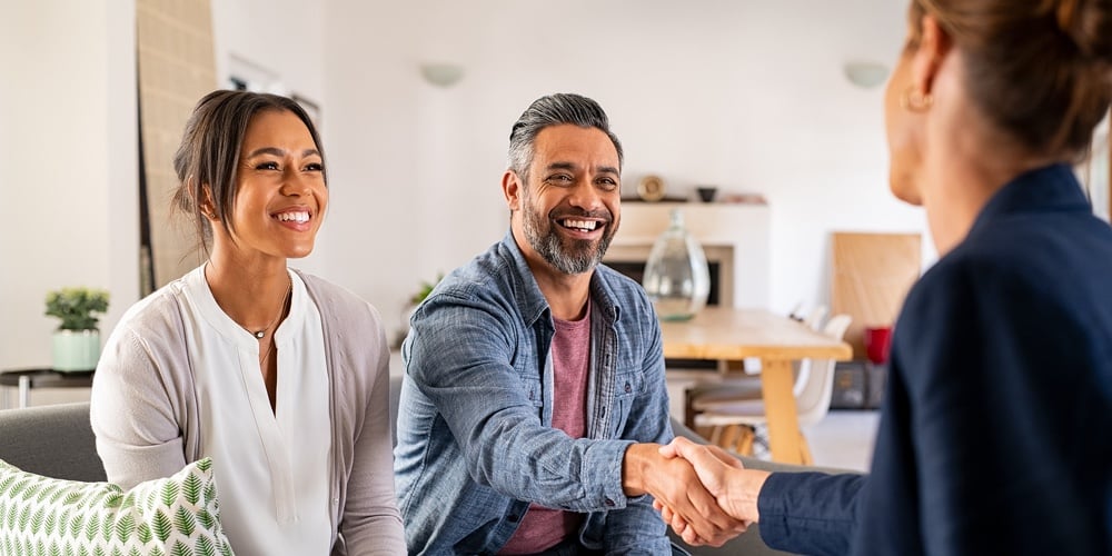 Mature indian man shaking hands with financial advisor at home. Happy smiling couple greeting broker