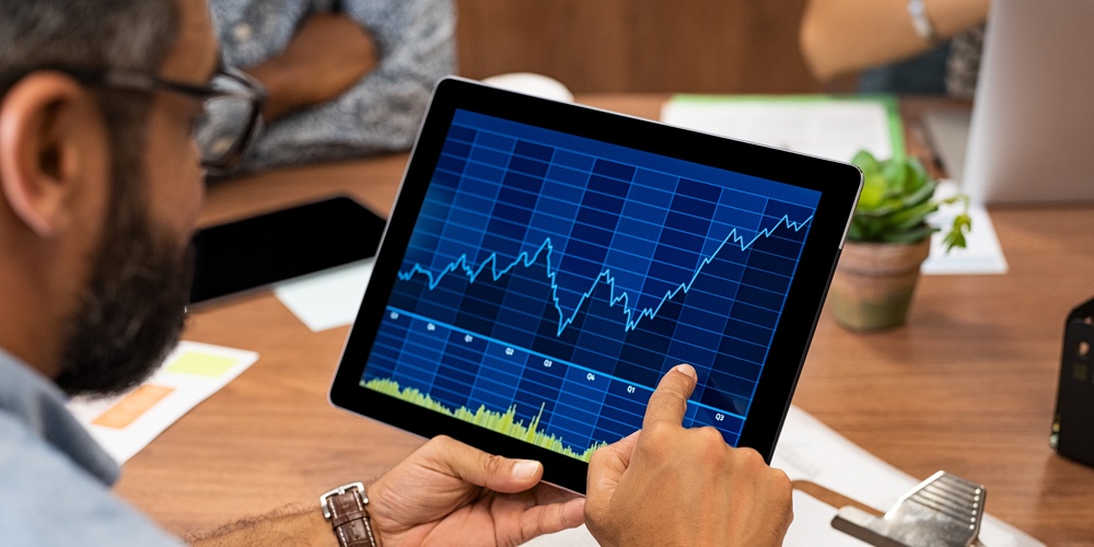 Mature latin businessman reading business graphs and stock charts on digital tablet. Rear view of bu