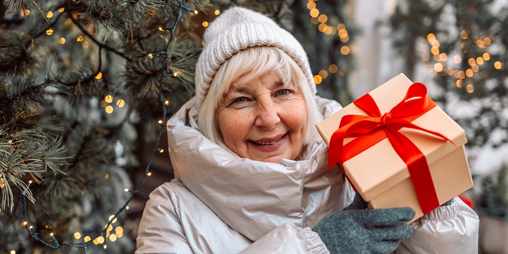 Merry Christmas And Happy Holidays. Senior Woman Having Fun With Surprise Gift Box Present Near Chri