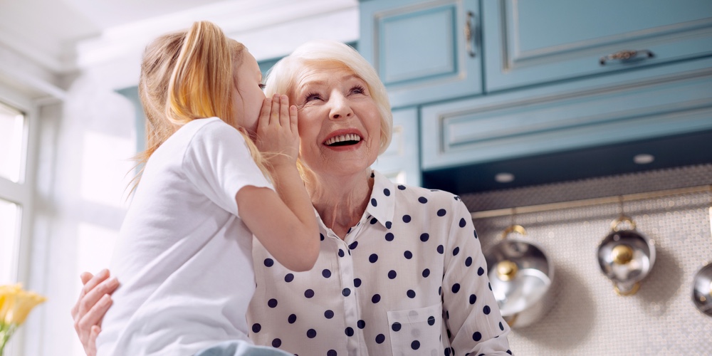 Our Little Secret. Pleasant Charming Elderly Woman Hugging Her Little Granddaughter And Listening To