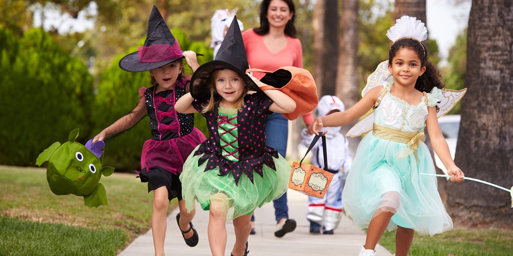Parent Taking Children Trick Or Treating At Halloween