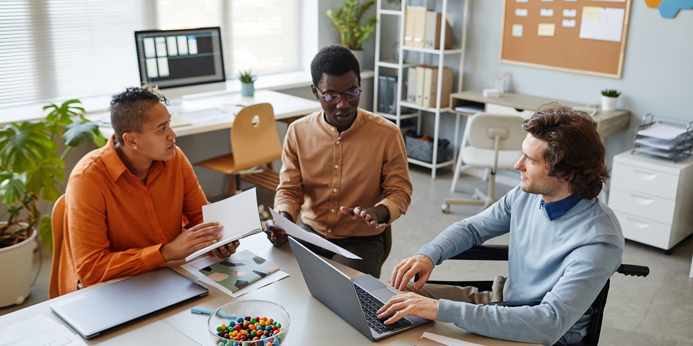 Portrait Of Diverse Business Team Discussing Project At Meeting Table Focus On Young Man Using Wheel|Portrait Of Diverse Business Team Discussing Project At Meeting Table Focus On Young Man Using Wheel