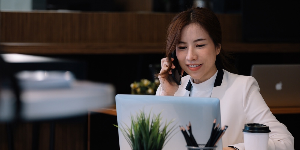Portrait Of Young Woman Smiling Cheerful Entrepreneur In Office Making Phone Call While Working With