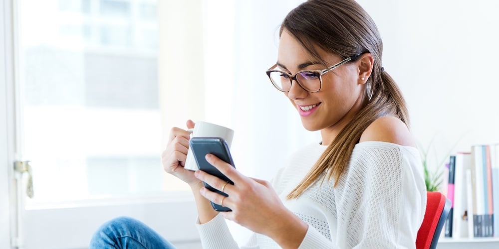 Pretty Young Woman Using Her Mobile Phone In The Office.