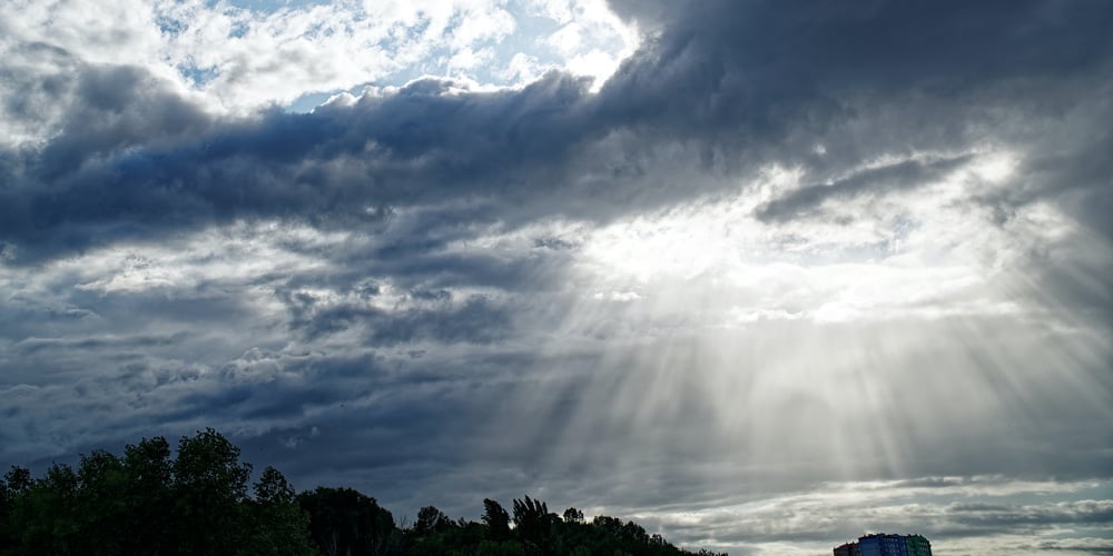 Rays Of Bright Sun Peep Out From Behind Dark Clouds