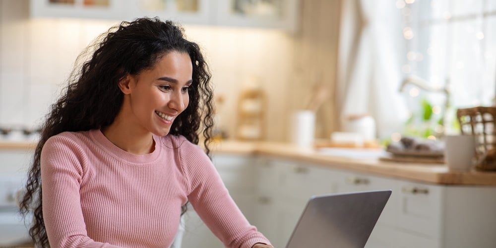 Remote Work. Beautiful Young Freelancer Lady Working With Laptop In Kitchen