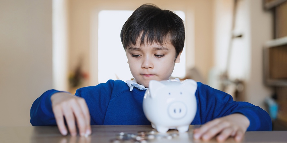 School Kid Putting Coins Into Piggy Bank