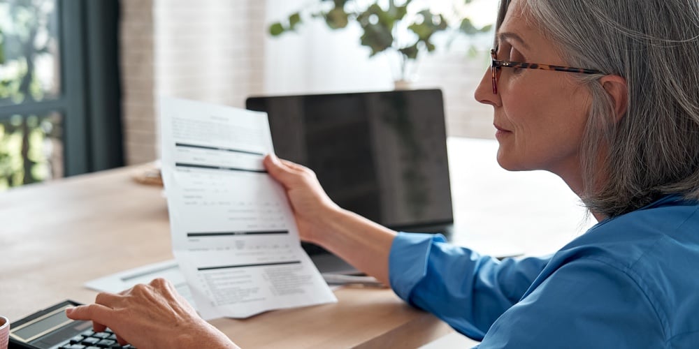 Senior Mature Business Woman Holding Paper Bill Using Calculator