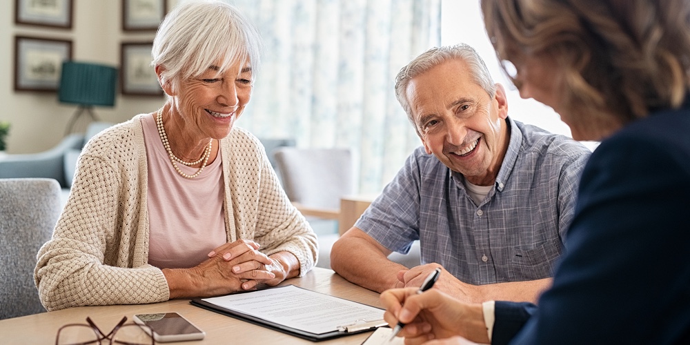 Senior couple planning their investments with financial advisor at home. Happy aged couple planning