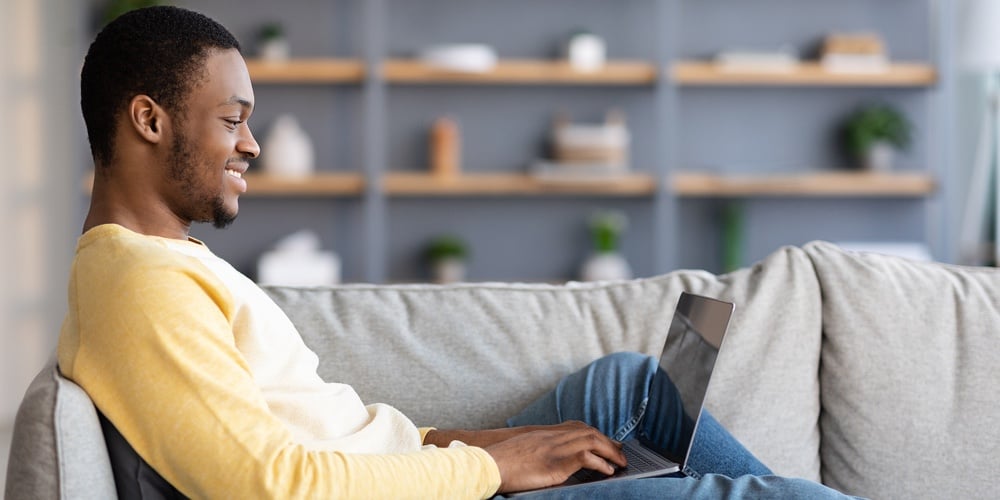 Side View Of Black Man Reclining On Couch In Living Room