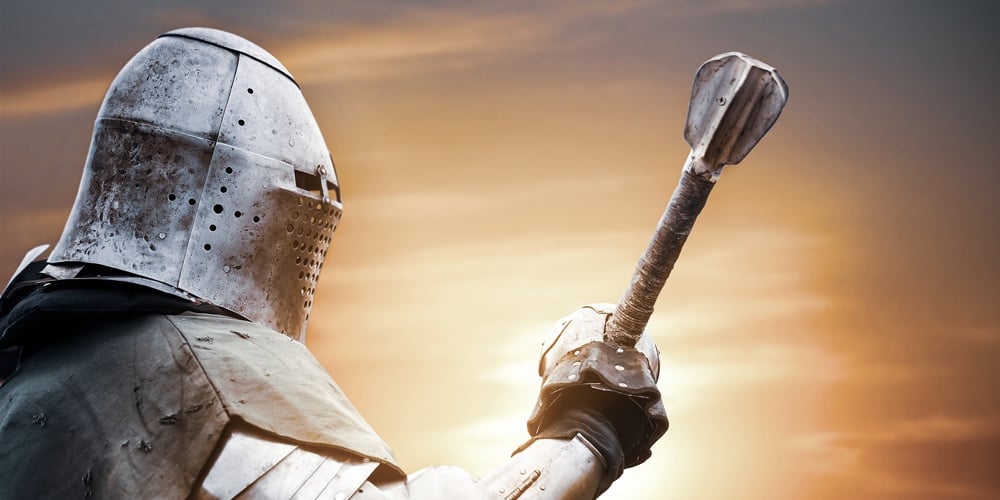 Side View Of Medieval Knight In Iron Armor Posing And Raising Big Sword. Close Up Portrait Of Brave