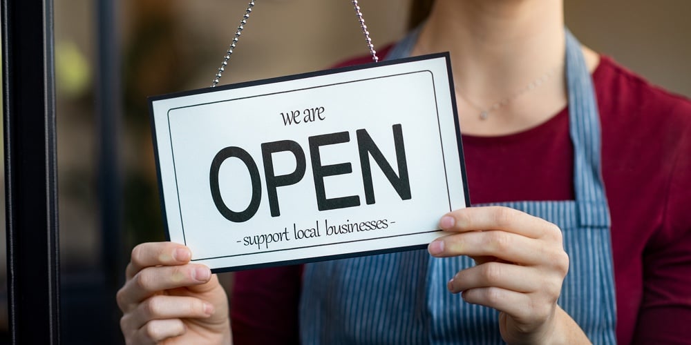 Small business owner smiling while turning the sign for the reopening of the place after the quarant