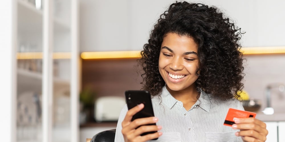 Smiling African American Teenage Girl With Curly Hair Holding Mobile Phone