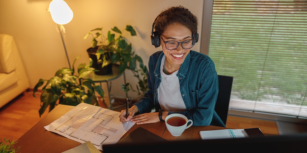 Smiling Afro American Woman Interior Designer In Headphones Works With Documents In Home Office