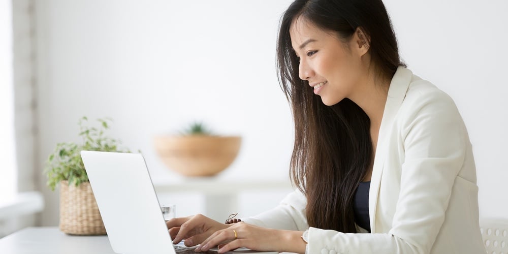 Smiling Young Asian Businesswoman Using Computer At Home Office Workplace