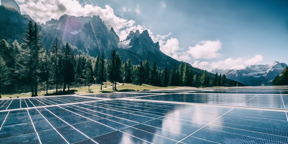 Solar Cell Panel In Country Landscape Against Sunny Sky And Mountain Backgrounds. Solar Power Is The
