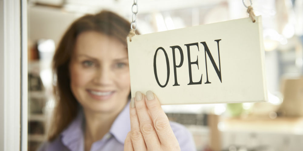 bigstock-Store-Owner-Turning-Open-Sign-84316688