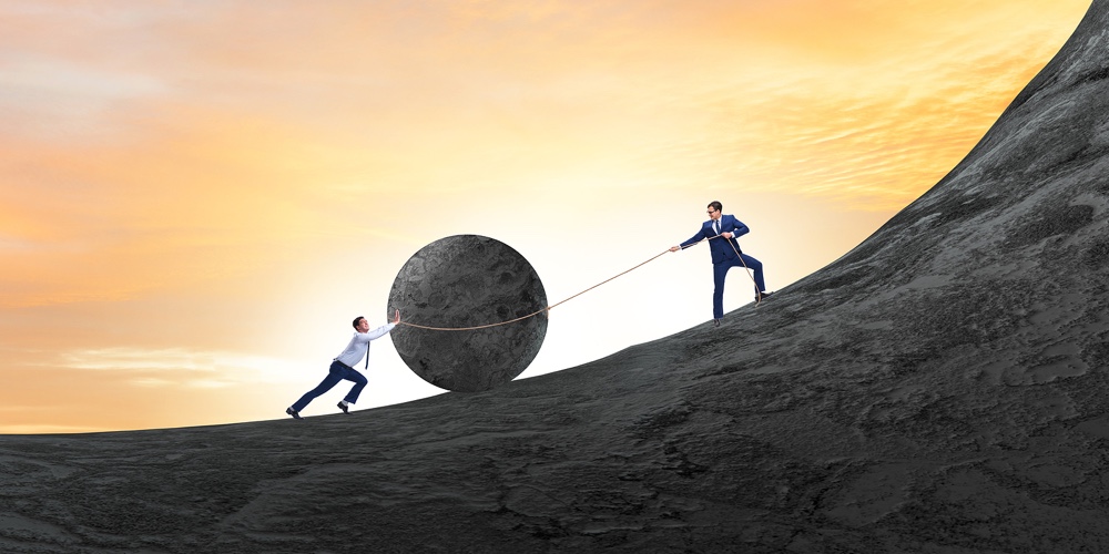 Teamwork example with business people pushing stone to top
