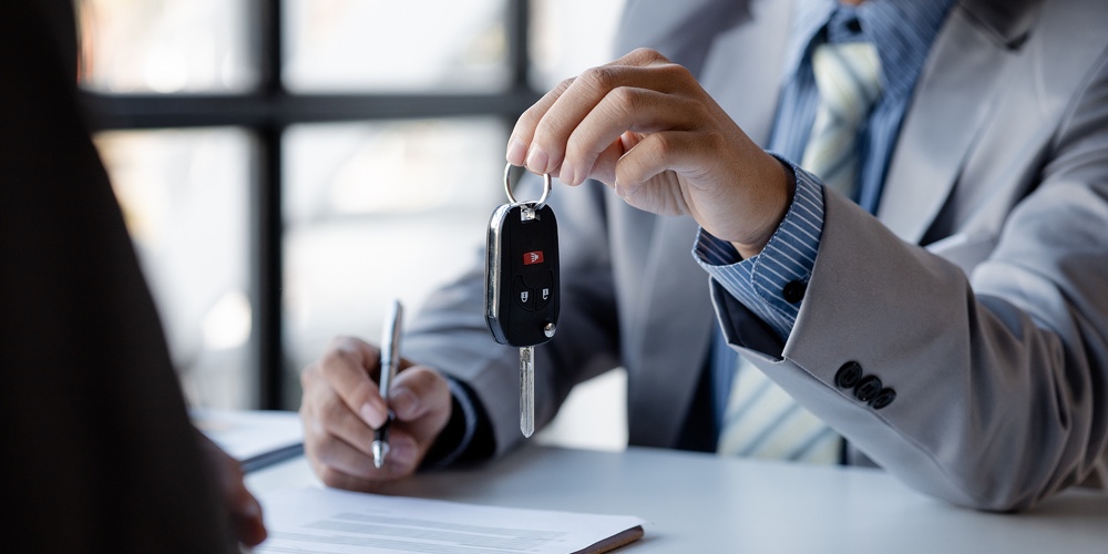 The Car Salesman Hands The Key To The Customer After Discussing The Details And Signing The Purchase