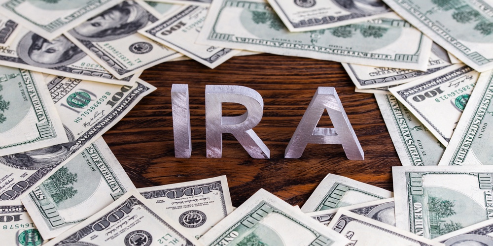 The Word Ira Made Of Silver Metal Letters On Wooden Background Surrounded By Us Dollar Banknotes