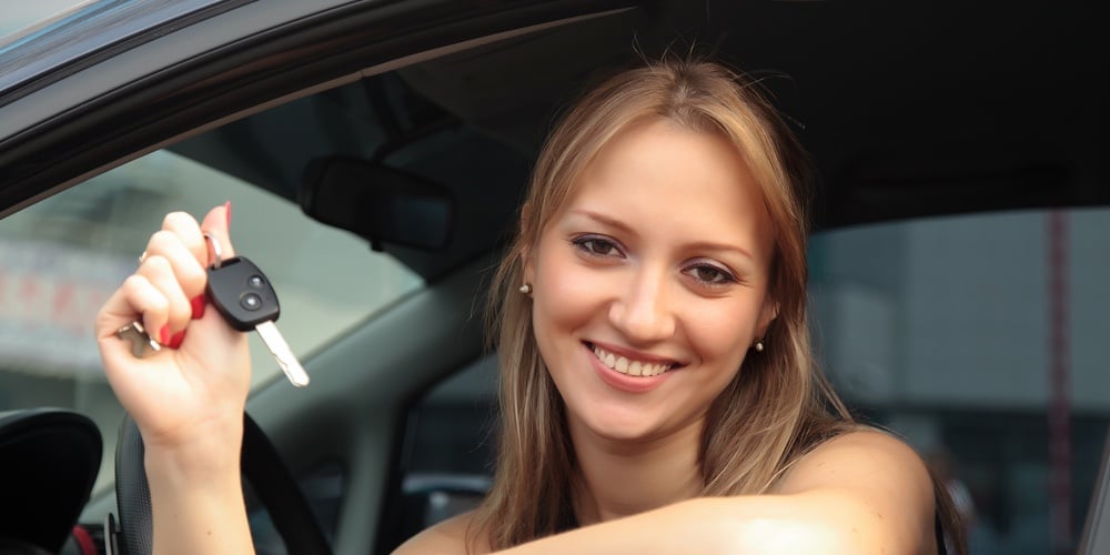The happy woman showing the key of her new car