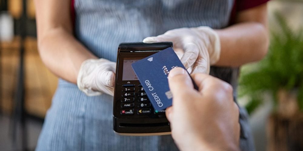 Waitress holding credit card reader machine and wearing protecti