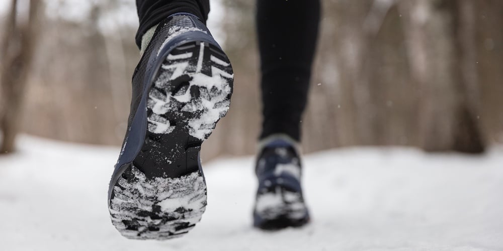 Winter exercise fitness lifestyle athlete walking with running shoes on snow and slippery ice needin
