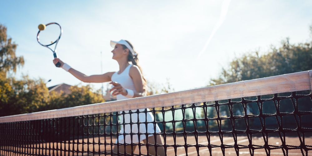 Woman getting a ball close to net on the tennis court