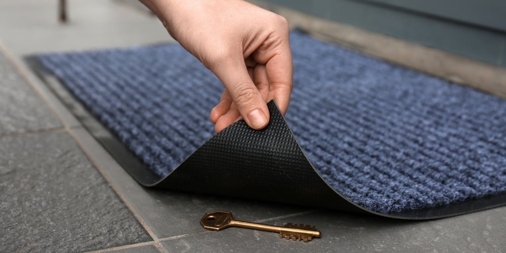 Woman’s Hand Lifting Door Mat To Reveal Key Hidden Underneath