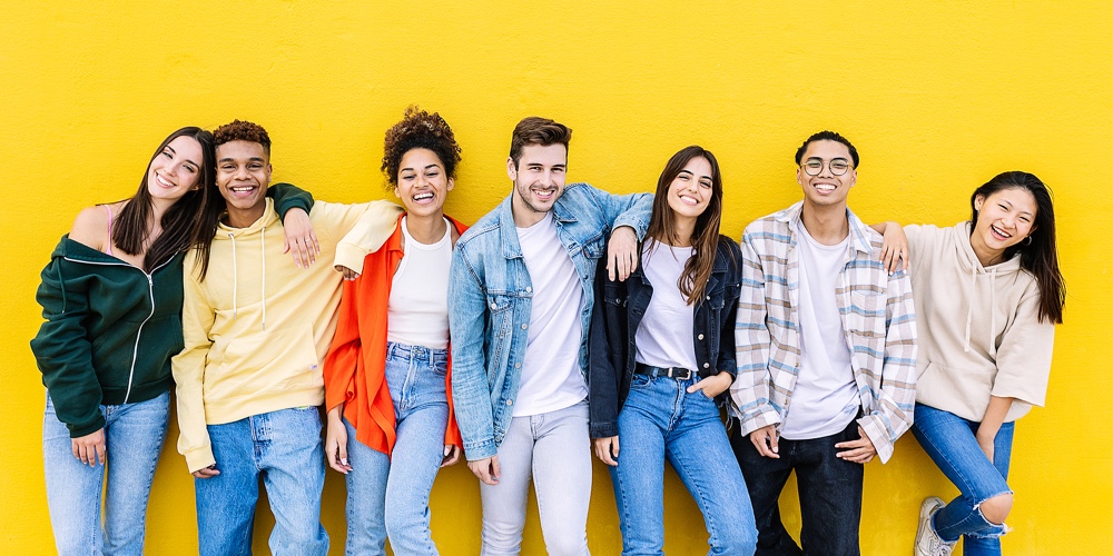 Young Adult United Group Of Multiracial Happy Friends Leaning On Yellow Wall – Community And Unity C