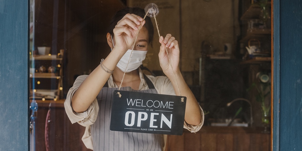 Young Asia Girl Wear Face Mask Turning A Sign From Closed To Open Sign On Door Looking Outside Waiti