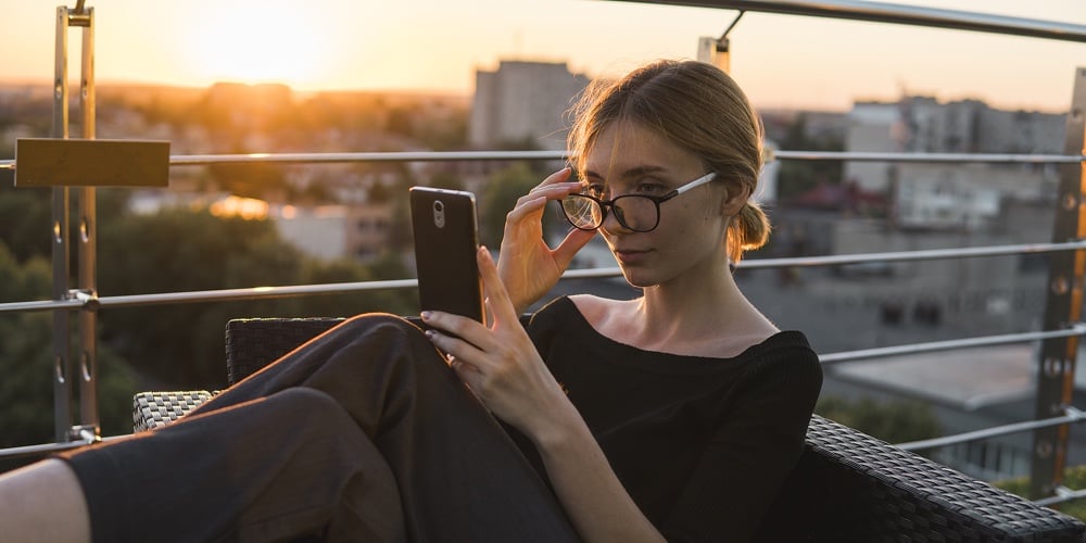 Young Business Woman Uses Phone. Good Looking Brunette Female Uses Online Banking On Smart Phone To