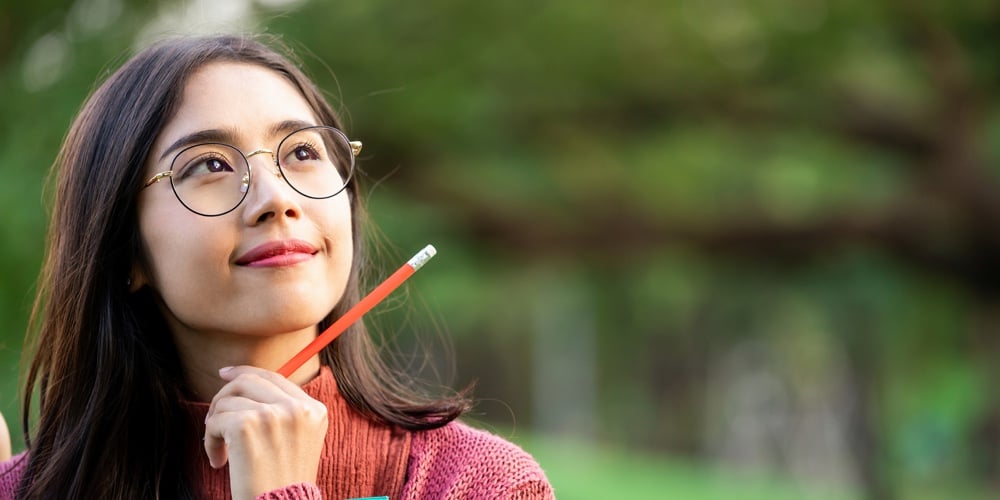 Young Creative Student Girl Thinking Or Planning Future Education While Holding Pencil In Hand. Crea