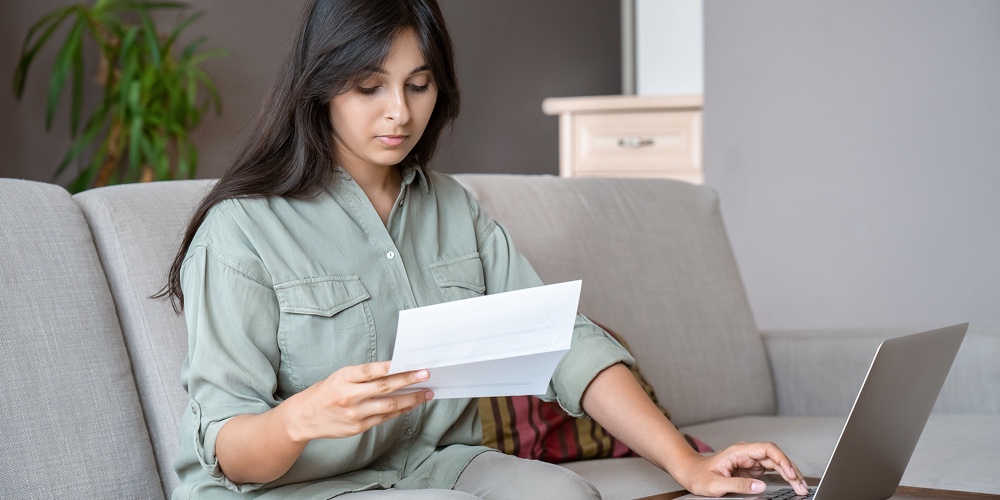 Young Indian Woman Holding Letter Using Laptop Computer Application Paying Bill Online On Website