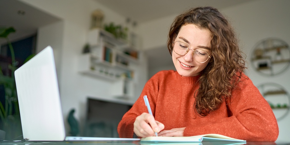 Young Smiling Pretty Woman Student Using Laptop Elearning Or Remote Working At Home Office Using Lap