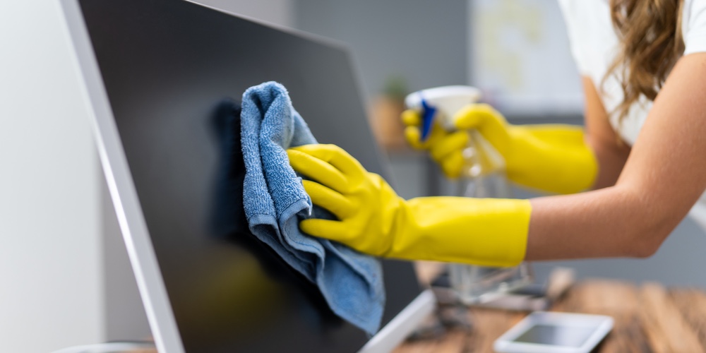 Young Worker Cleaning Desk With Rag In Office