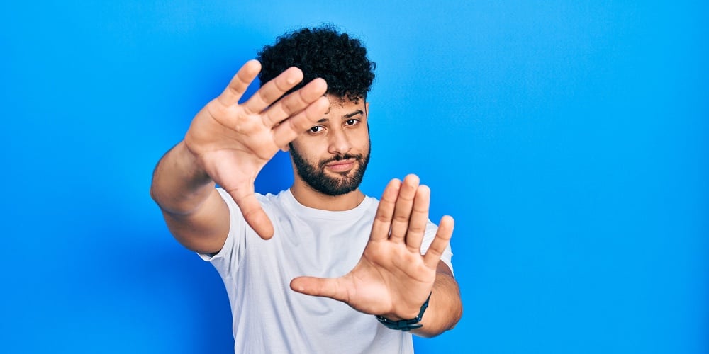 Young arab man with beard wearing casual white t shirt doing frame using hands palms and fingers