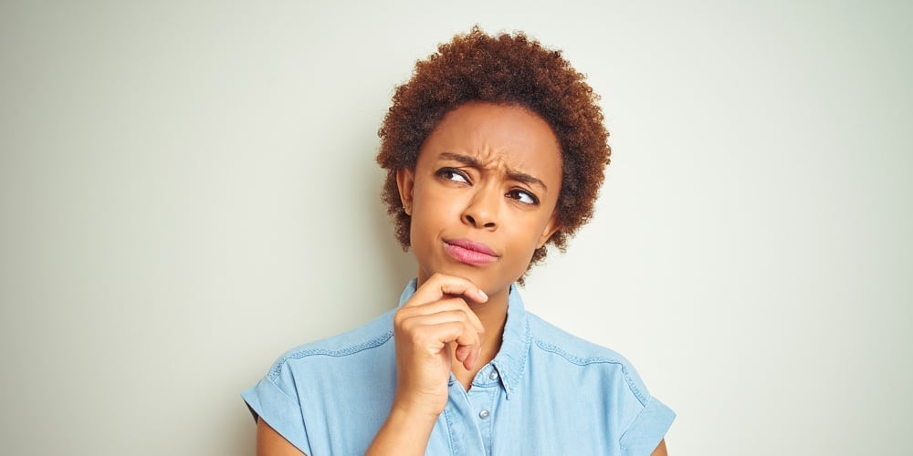 Young beautiful african american woman with afro hair over isolated background with hand on chin thi
