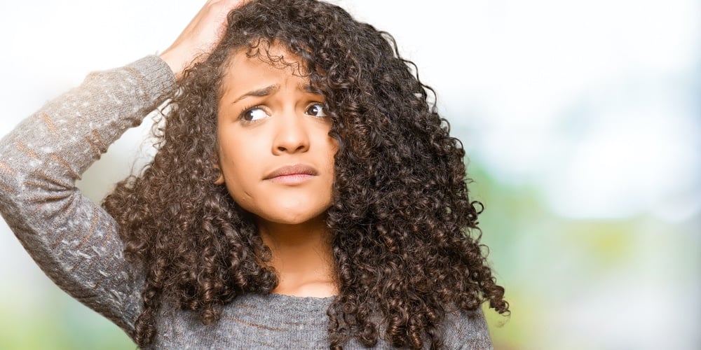 Young beautiful woman with curly hair wearing grey sweater confuse and wonder about question. Uncert