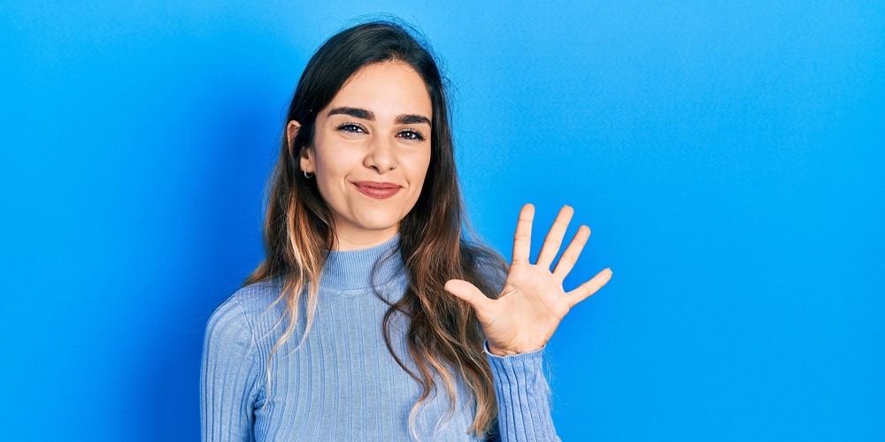 Young hispanic girl wearing casual clothes showing and pointing up with fingers number five while sm
